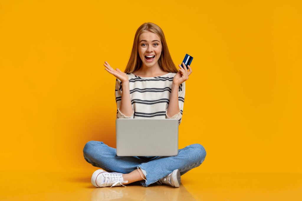 Excited girl using laptop and credit card for purchasing online