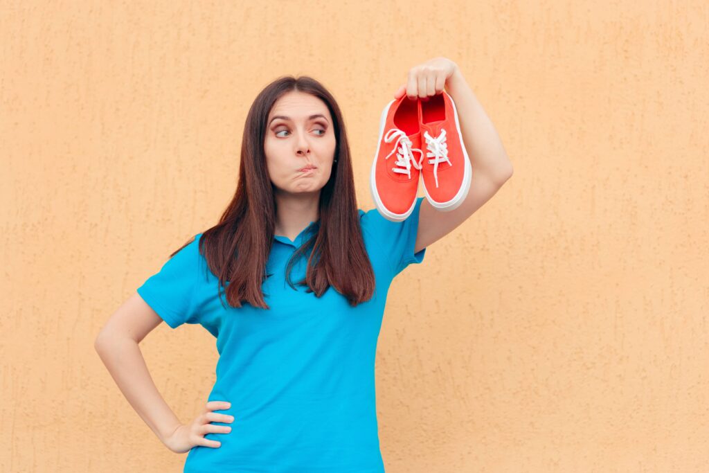 Unhappy Woman Holding a Pair of Red Sport Shoes