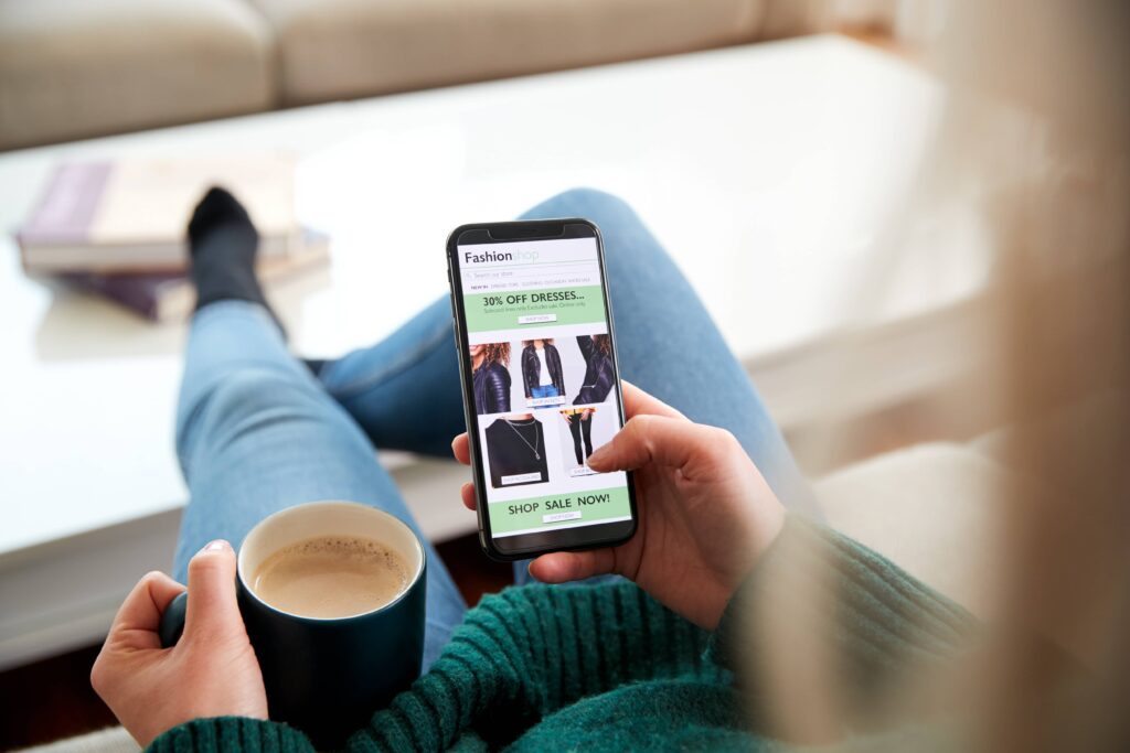 Person sat on sofa with a coffee scrolling online shopping